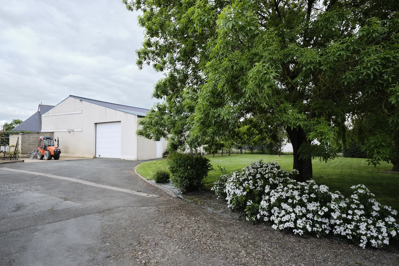 Entrée et jardin d'un domaine viticole menant vers un chai