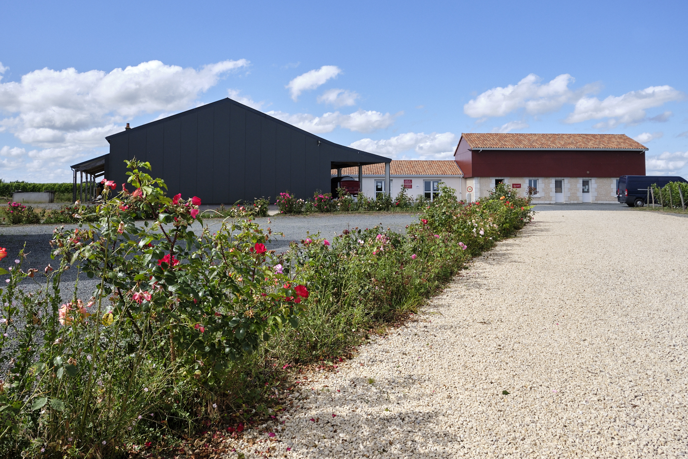 La belle entrée d'un domaine viticole, avec oenotourisme, hangar à matériel et un parterre de fleurs