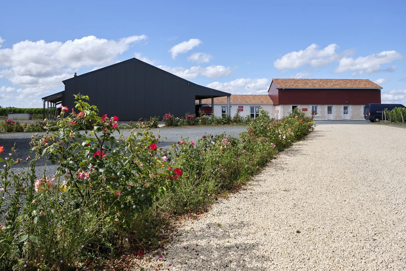 La belle entrée d'un domaine viticole, avec oenotourisme, hangar à matériel et un parterre de fleurs
