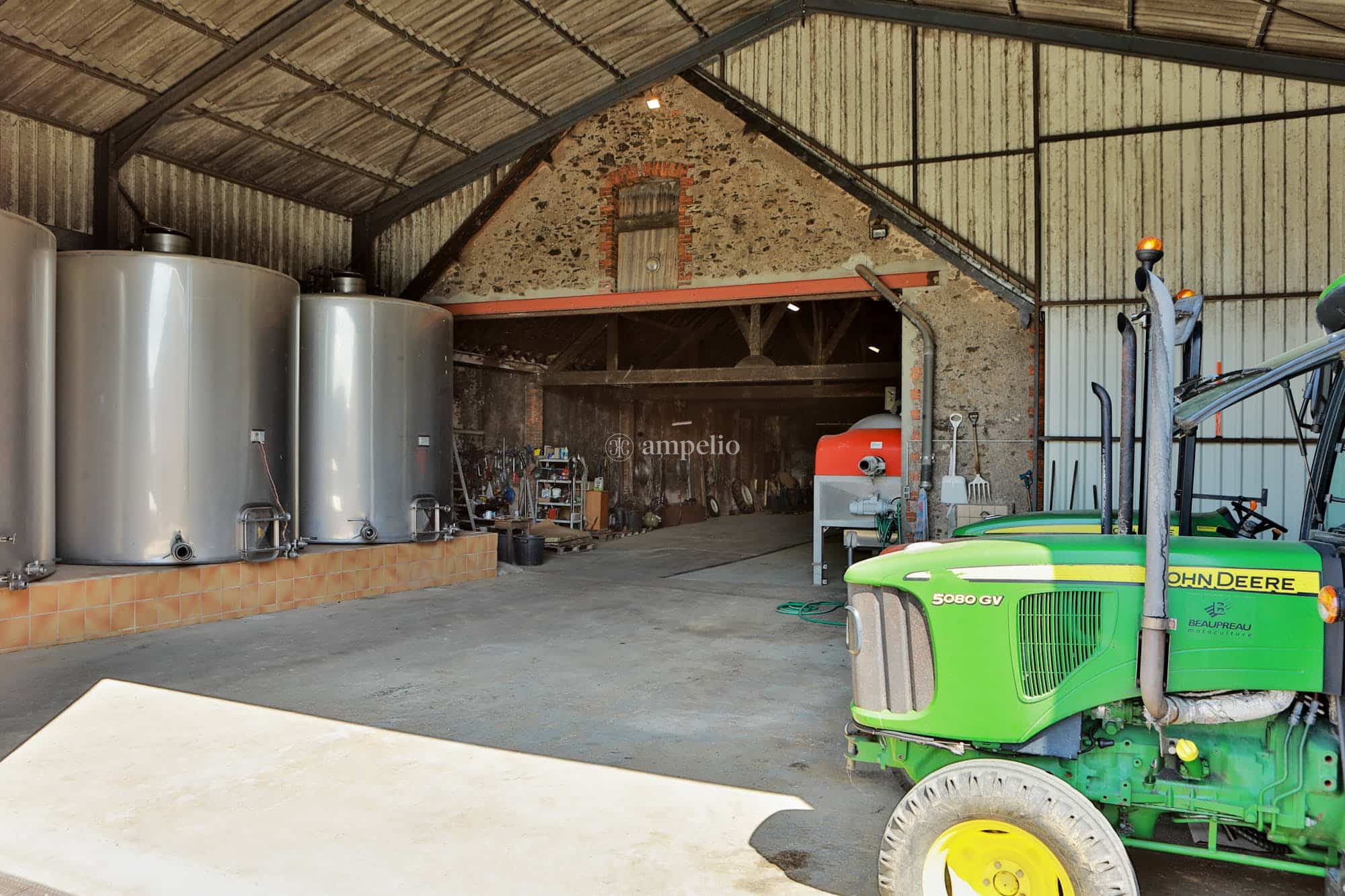 Un batiment d'un domaine viticole avec cuves en inox, tracteurs et matériel